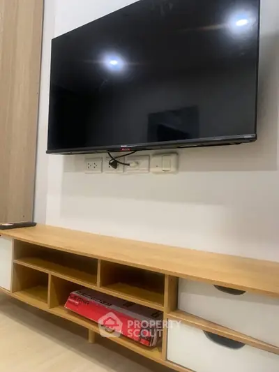 Modern living room with wall-mounted TV and stylish wooden console.