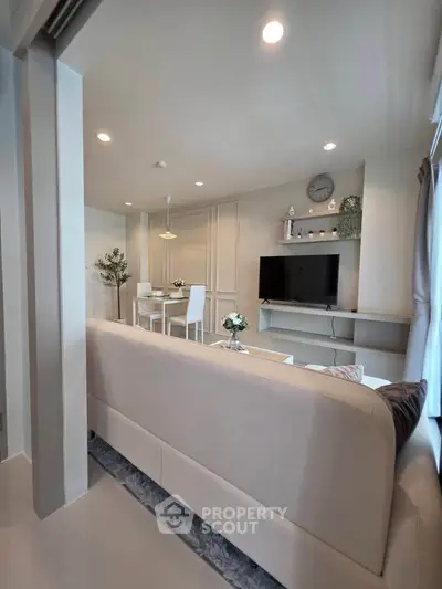 Modern living room with sleek furniture and wall-mounted TV in a bright, airy space.