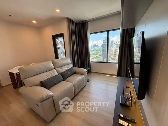 Modern living room with city view, featuring a cozy sofa and sleek TV setup.
