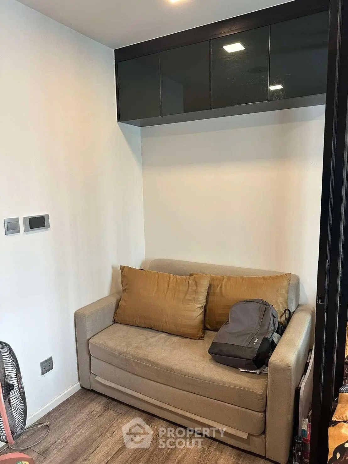 Cozy small living room with modern sofa and wall-mounted cabinets, perfect for compact urban living.
