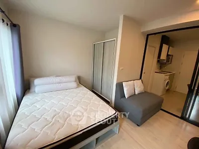 Modern bedroom with cozy bed and adjacent kitchenette in stylish apartment.