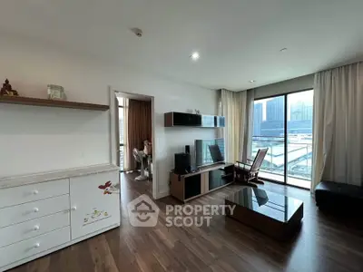 Spacious living room with modern decor and city view balcony in high-rise apartment.