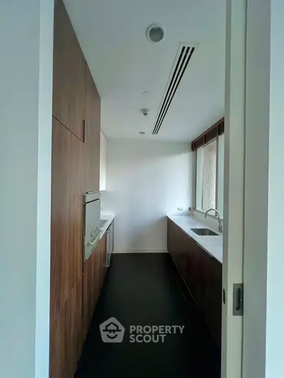 Sleek modern kitchen with wood cabinetry and ample natural light, perfect for culinary enthusiasts.