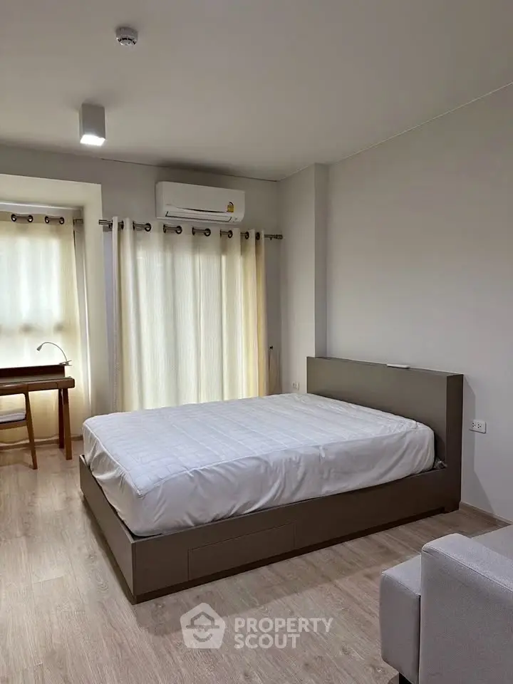 Modern bedroom with minimalist design, featuring a comfortable bed and natural light from large windows.