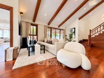 Luxurious living room with wooden beams, plush seating, and elegant decor in a spacious open layout.