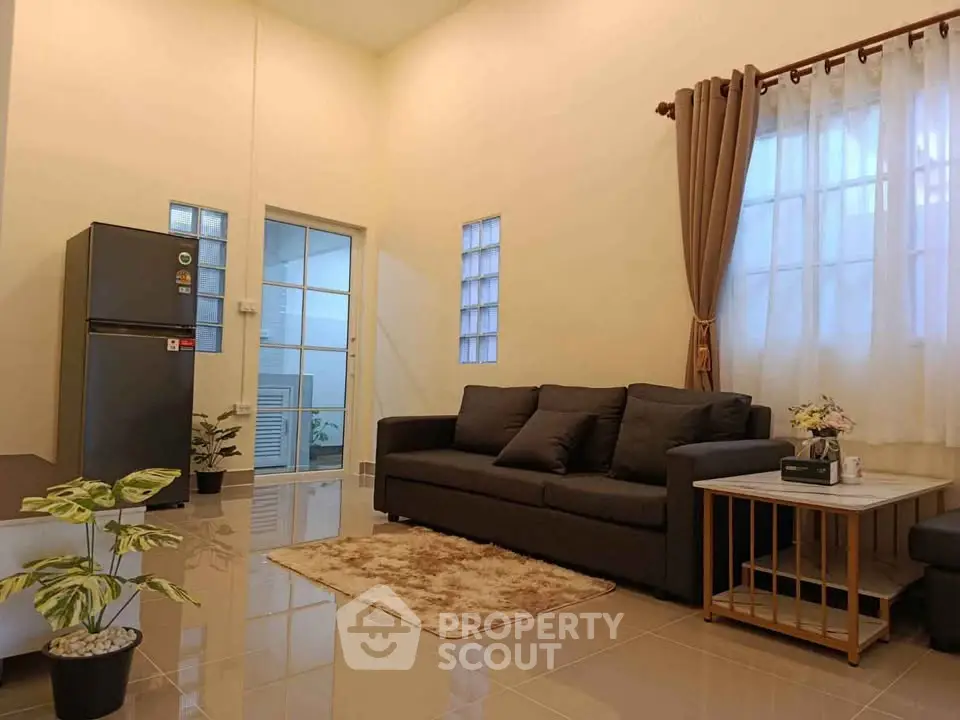 Modern living room with sleek black sofa and stainless steel fridge