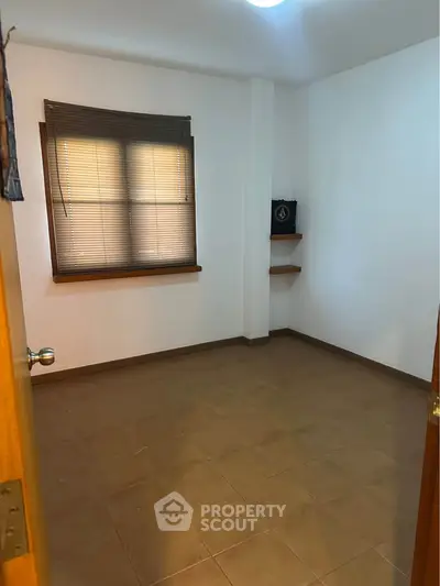 Spacious empty room with tiled floor and window blinds, perfect for customization.