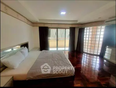 Spacious bedroom with large windows and elegant wooden flooring
