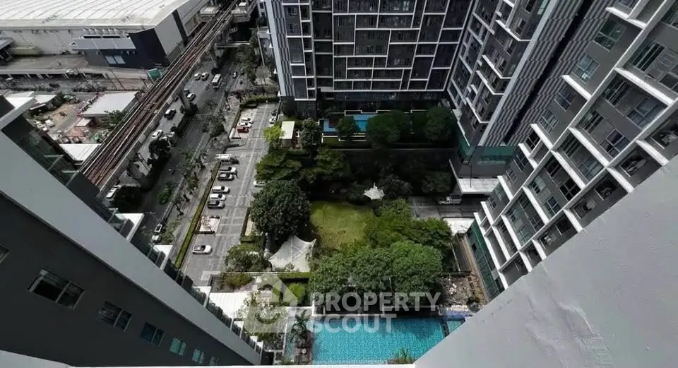 Stunning aerial view of modern high-rise building with lush garden and pool, perfect for urban living.