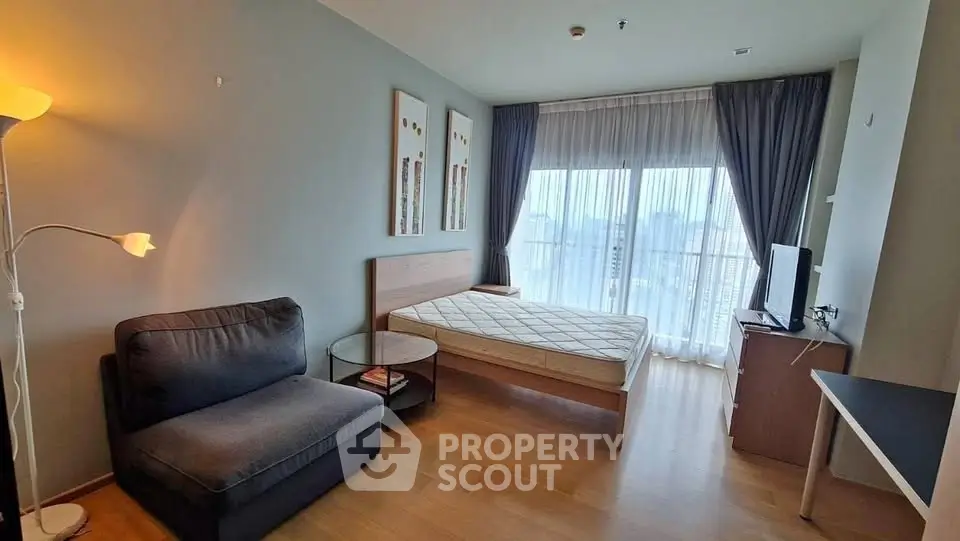 Modern bedroom with large window and cozy furnishings in a stylish apartment.