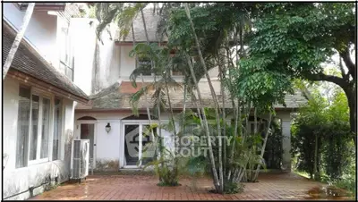 Charming colonial-style home with lush greenery and spacious courtyard, perfect for serene living.
