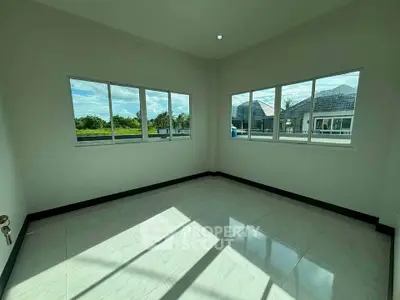 Bright empty room with large windows and tiled floor, offering a serene view of the outdoors.