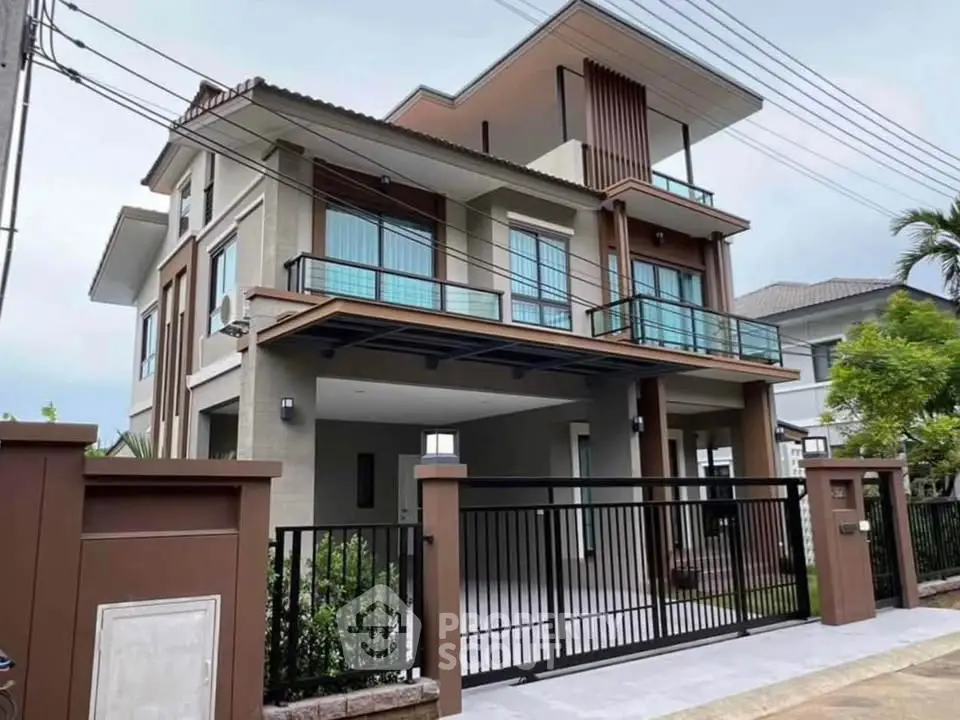 Modern two-story house with sleek design and spacious balcony in a suburban neighborhood.