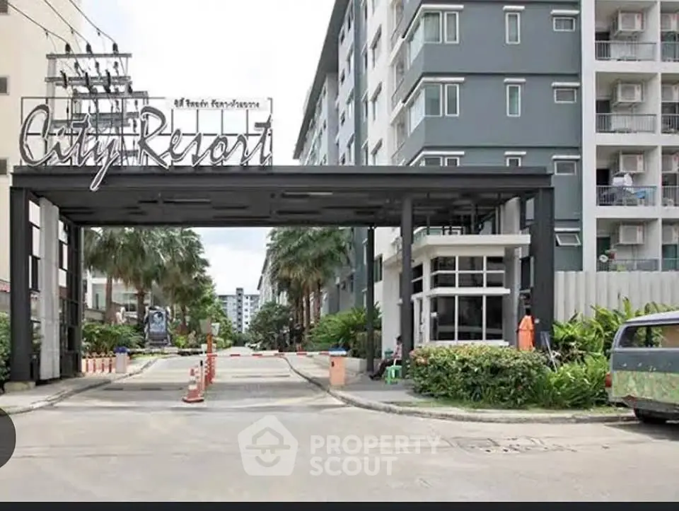 Modern city resort entrance with palm-lined driveway and contemporary architecture.