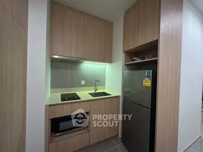 Modern compact kitchen with sleek wooden cabinets and stainless steel appliances