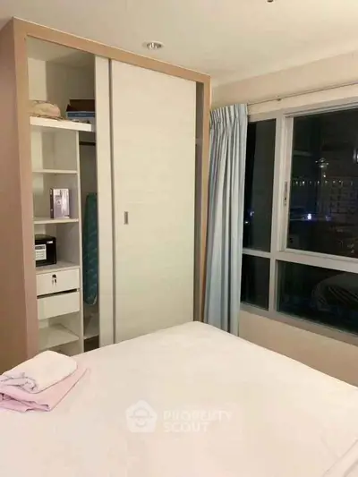 Cozy bedroom with built-in wardrobe and large window offering city view.