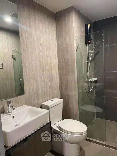 Modern bathroom with glass shower and sleek fixtures in contemporary apartment.