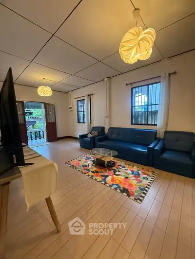 Spacious living room with modern lighting and colorful rug in cozy home.