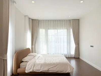 Spacious bedroom with elegant curtains and modern bed in a bright, minimalist design.