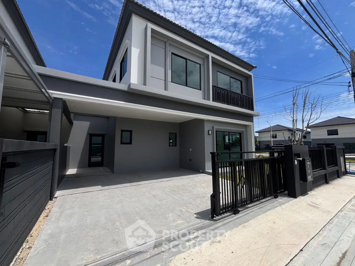 Modern two-story house with sleek design and spacious driveway under a clear blue sky.