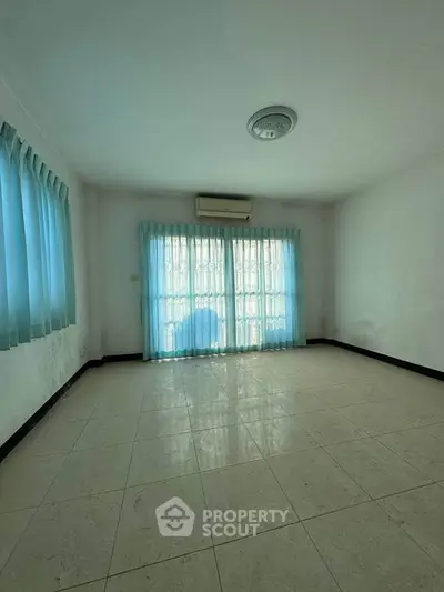 Spacious empty room with tiled floor and large windows, perfect for customization.