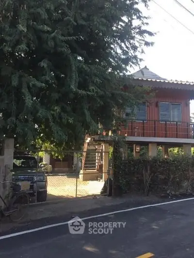 Charming two-story wooden house with lush greenery and a spacious front yard.