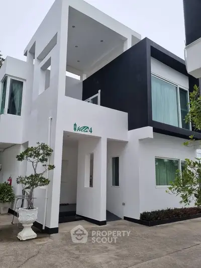 Modern white and black two-story house with large windows and minimalist design.