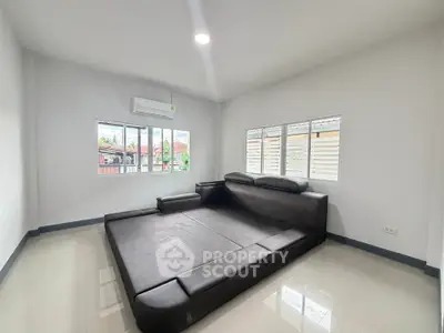 Spacious living room with modern black sofa and large windows offering natural light.