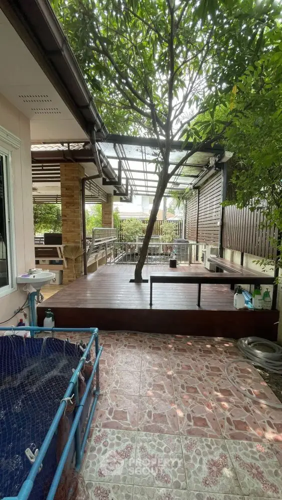 Charming outdoor patio with wooden deck and lush greenery, perfect for relaxation and entertaining.