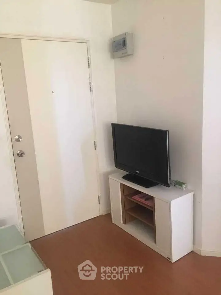 Cozy living room corner with modern TV setup and sleek wooden flooring.