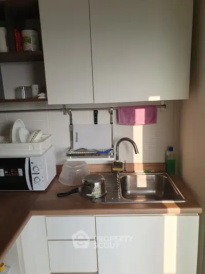 Compact kitchen with modern appliances and wooden countertop