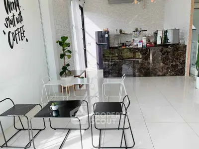 Chic modern cafe interior with sleek black and white furniture, marble counter, and stylish decor.
