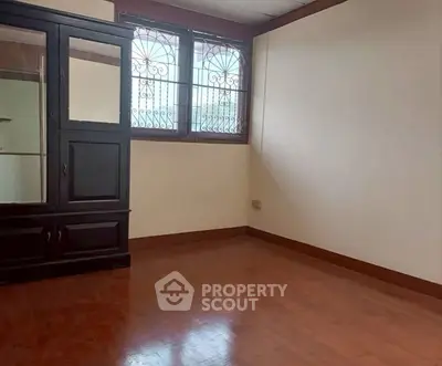 Spacious empty room with wooden flooring and large window, perfect for customization.