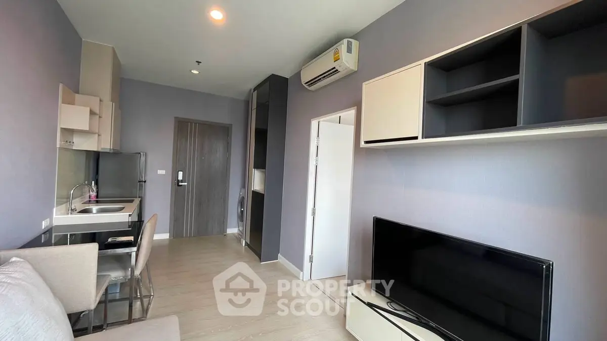 Modern living room with sleek furniture and built-in storage, featuring a wall-mounted TV and air conditioning.