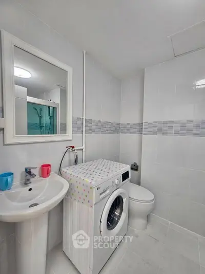 Modern bathroom with washing machine and sleek white tiles
