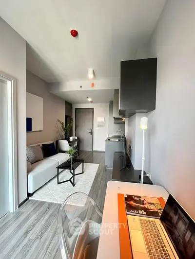 Modern living room with sleek furniture and open layout, featuring a cozy workspace and stylish decor.