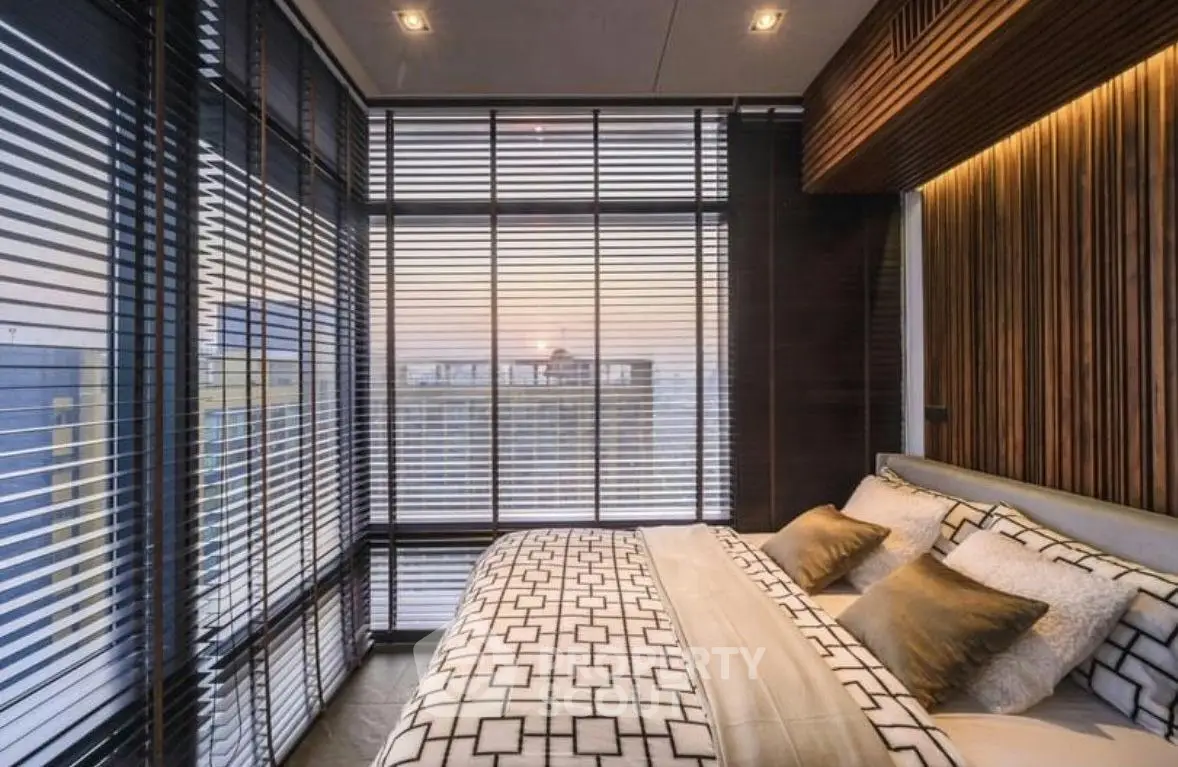Luxurious bedroom with floor-to-ceiling windows offering stunning city views and elegant decor.