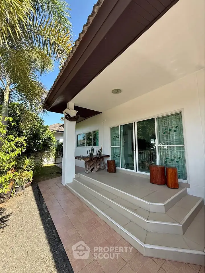 Charming single-story home with inviting front porch and lush garden, perfect for relaxing outdoors.