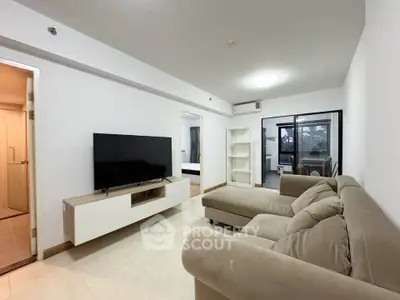 Spacious modern living room with plush sofa and large TV, perfect for relaxation and entertainment.