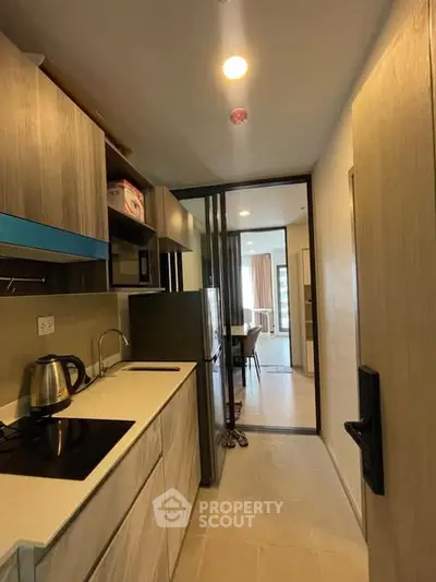 Modern kitchen with sleek cabinetry and open layout leading to dining area.