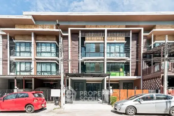 Modern townhouse facade with large windows and balconies, featuring a contemporary architectural design.