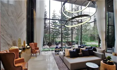 Luxurious modern living room with high ceilings and garden view, featuring elegant furniture and stylish decor.