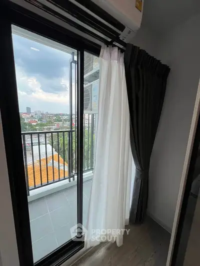 Charming balcony view with sliding glass doors and elegant curtains, perfect for enjoying cityscapes.