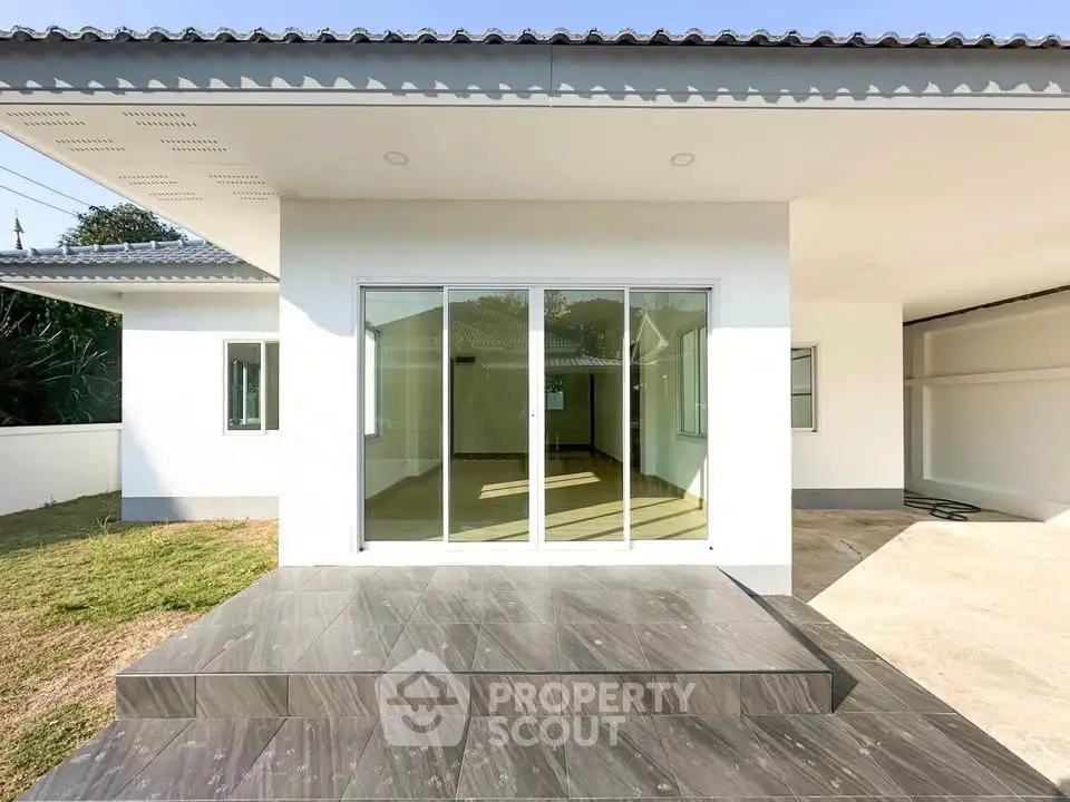 Modern minimalist home exterior with sliding glass doors and spacious patio