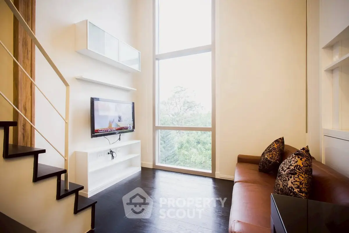 Modern living room with high ceilings and large windows offering a scenic view.