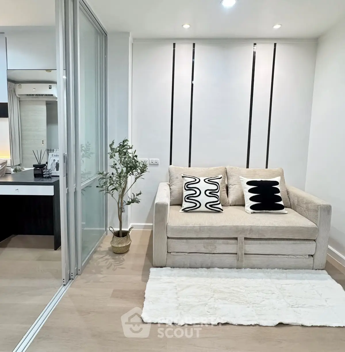 Modern living room with cozy beige sofa and stylish decor in a compact apartment.