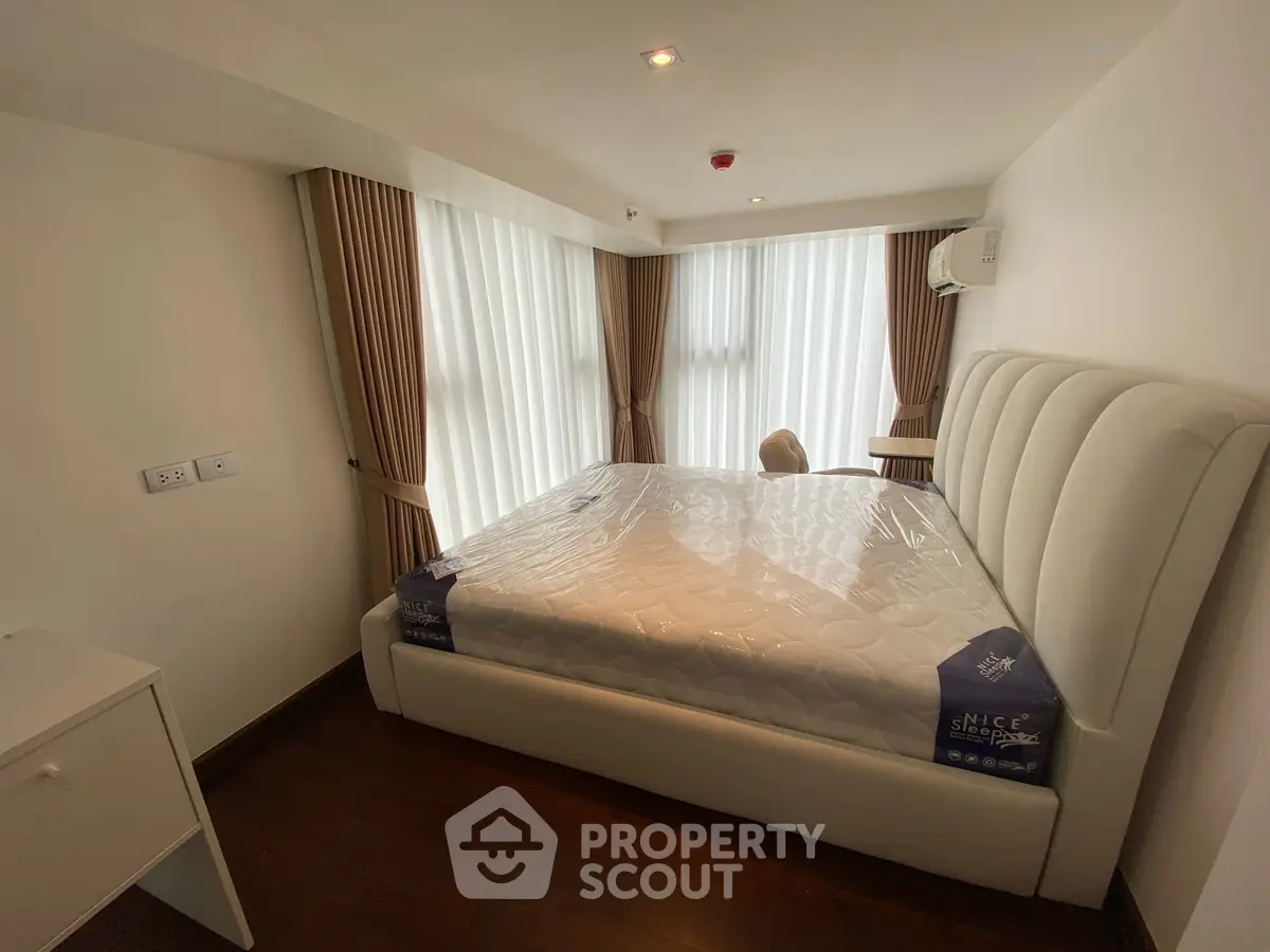 Modern bedroom with large windows and elegant curtains in a stylish apartment.