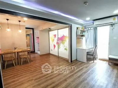 Spacious open-plan living area with dining space and world map decor, featuring modern lighting and wooden flooring.