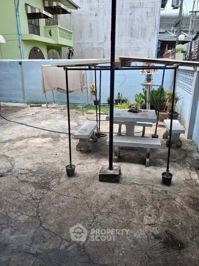 Charming outdoor patio with concrete seating and lush plants, perfect for relaxation and gatherings.