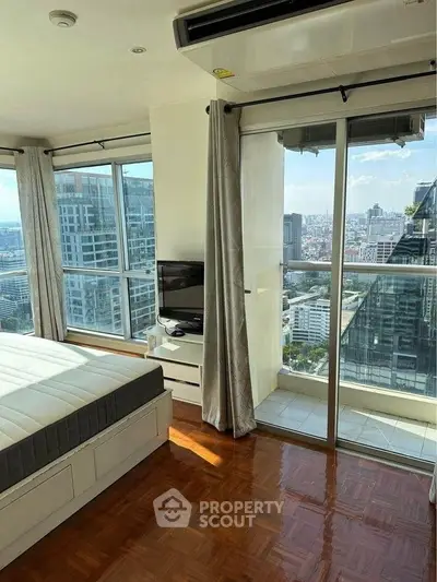 Luxurious bedroom with stunning city view and balcony access in high-rise apartment.